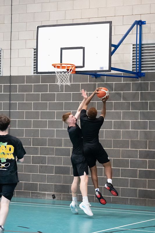 Two players going up at the rim, one attempting a block
