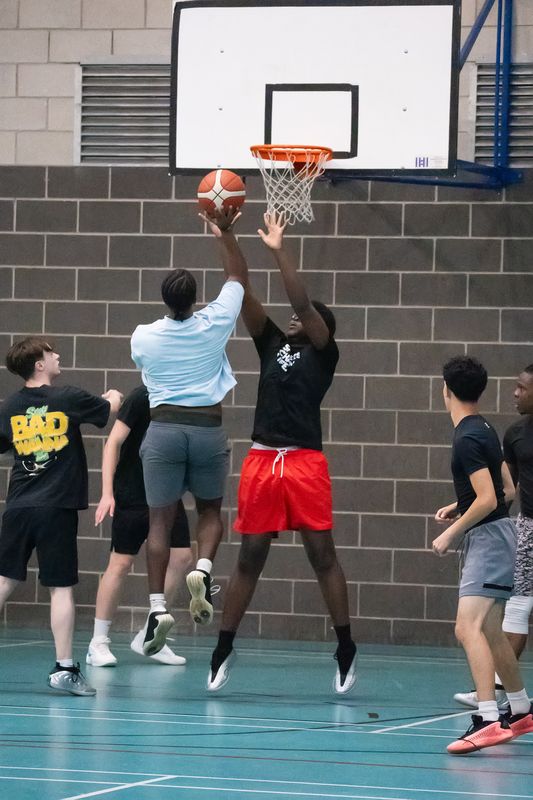 A player rising for a shot under the basket while a defender contests