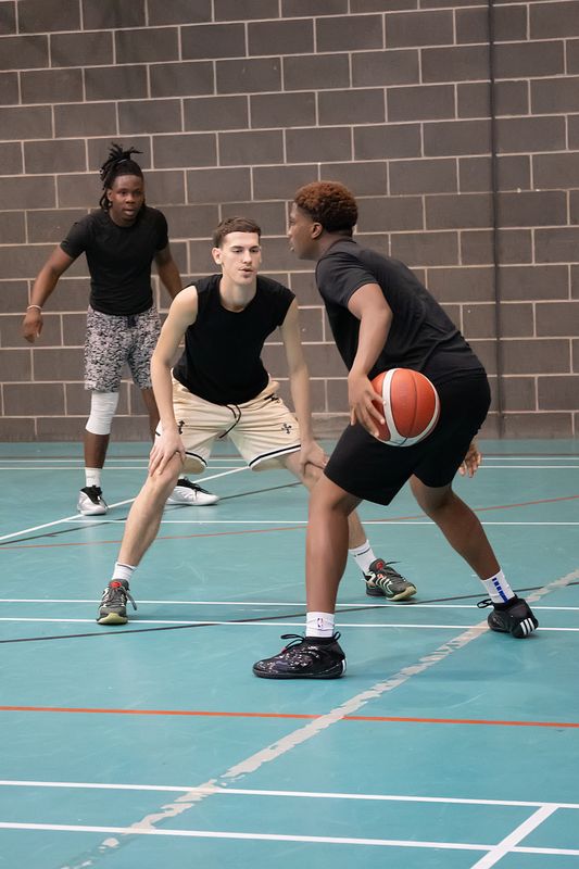 A defender in a low stance guarding a player with the ball