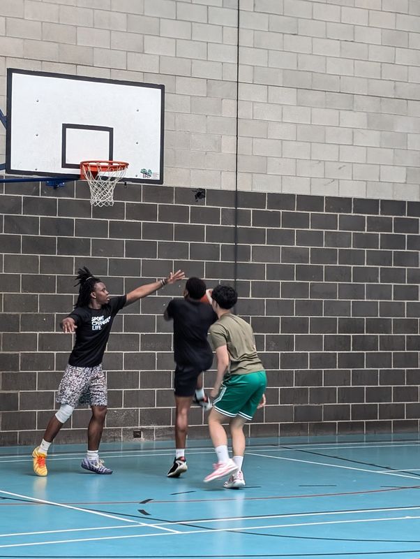Three players working the ball on the wing under the basket