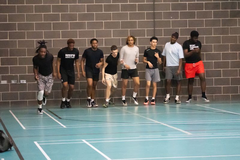 Players lined up along the sports hall wall for a warm-up drill